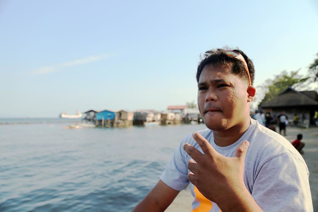 A man speaks as he looks out onto a body of water.